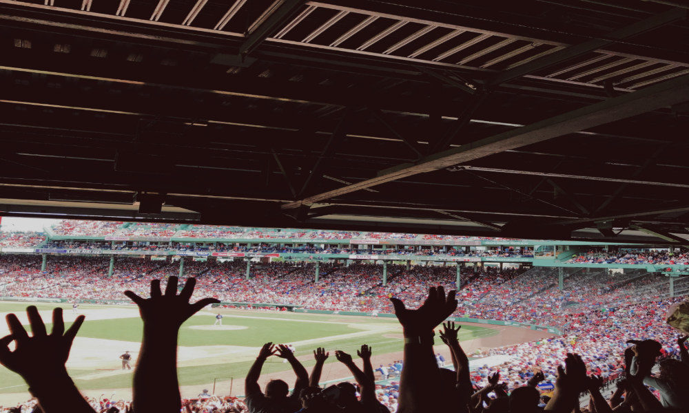 Excited fans in stadium raising hands. 